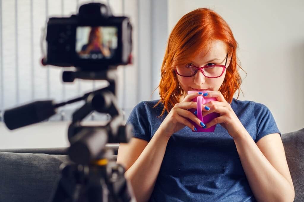 Orange-haired girl in front of a professional video camera